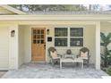 Inviting front porch with chairs and wood door at 20 Warwick Ave, Ormond Beach, FL 32174