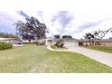 Inviting single-story home featuring a lush green lawn and a long driveway leading to the attached garage at 2307 Needle Palm Dr, Edgewater, FL 32141