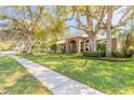 Elegant home with lush lawn, mature trees, arched entryway, and a fenced front yard at 6049 Sabal Hammock Cir, Port Orange, FL 32128