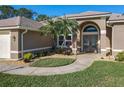 Inviting front entrance with double doors, complemented by tropical plants and manicured landscaping at 6456 Cypress Springs Pkwy, Port Orange, FL 32128