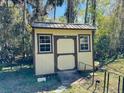 Backyard storage shed featuring neutral colors, a secure door, and windows for natural light and ventilation at 1136 Elizabeth St, New Smyrna Beach, FL 32168
