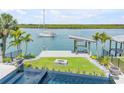 Waterfront backyard featuring a private dock, fire pit, and stunning pool with mosaic tile at 1194 N Peninsula, New Smyrna Beach, FL 32169