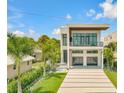 Modern two-story home featuring a balcony, stylish garage doors and a beautifully landscaped front yard with palm trees at 1194 N Peninsula, New Smyrna Beach, FL 32169