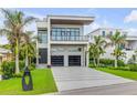Beautiful modern home with lush green grass, sleek driveway, and tropical landscaping at 1194 N Peninsula, New Smyrna Beach, FL 32169