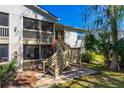 Condo with screened porches and wooden stairs next to lush trees and landscaping on a sunny day at 1600 Big Tree Rd # I2, South Daytona, FL 32119
