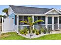 Side view of a home with a white picket fence, well-manicured lawn, and small palm tree at 216 Kirkland Dr, New Smyrna Beach, FL 32169