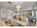 Bright dining room with a chandelier, glass table, mirrored wall, and an open concept view of the living room at 2700 N Peninsula Ave # 513, New Smyrna Beach, FL 32169