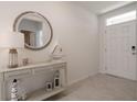 Inviting foyer featuring a decorative console table, round mirror and neutral color scheme at 3245 Carpentaria Dr, New Smyrna Beach, FL 32168