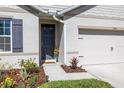 Welcoming front entrance with a gray front door, lovely flowerbeds, and a glimpse of the garage at 3245 Carpentaria Dr, New Smyrna Beach, FL 32168