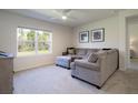 Bright living room with plush carpet, a comfortable sofa, and a large window showcasing the outdoors at 3245 Carpentaria Dr, New Smyrna Beach, FL 32168