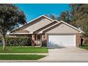 Charming one-story home featuring a well-manicured lawn, a brick facade, and a two-car garage at 549 Coral Trace Blvd, Edgewater, FL 32132