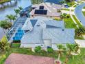 Aerial view of a home with a gray roof, screened pool, beautiful landscaping, and lake view at 6665 Merryvale Ln, Port Orange, FL 32128