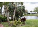 Beautiful backyard view with lush landscaping, pond, and mature palm trees on a cloudy day at 731 Pine Shores Cir, New Smyrna Beach, FL 32168