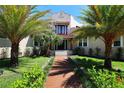 Charming Mediterranean-style home with a vibrant green lawn, beautiful palm trees, and a welcoming walkway at 746 N Halifax Ave, Daytona Beach, FL 32118