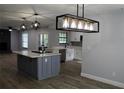 Modern kitchen features a gray island with cooktop, white cabinets, stainless steel appliances, and modern light fixtures at 855 Sugar House Dr, Port Orange, FL 32129