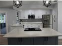 Bright kitchen with white cabinets, gray backsplash, a stainless steel fridge and a large island with cooktop at 855 Sugar House Dr, Port Orange, FL 32129