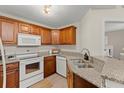 Traditional-style kitchen with wood cabinets, granite countertops, and white appliances at 898 Baybreeze Way # 880, New Smyrna Beach, FL 32169