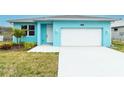 Charming turquoise single-story home with a white garage door, landscaped yard, and a well-lit front entrance at 113 Douglas St, Edgewater, FL 32141