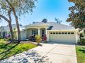 Charming single-story home featuring a manicured lawn, mature landscaping, and attached two-car garage at 5986 Heron Pond Dr, Port Orange, FL 32128