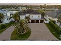 Aerial view of a two-story home with palm trees, a three-car garage, and waterfront views at 1212 Commodore Dr, New Smyrna Beach, FL 32168