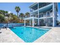 Home exterior with outdoor pool, volleyball net and lounge area with multiple seating arrangements at 1373 N Atlantic Ave, New Smyrna Beach, FL 32169