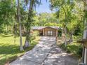 Attractive home exterior with stone accents, lush trees, and a lengthy driveway leading to a serene setting at 1663 Hideaway Ln, Edgewater, FL 32132