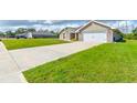Long driveway and manicured lawn leading to a brick home with a white garage door at 208 Lagoon Mist Ct, Oak Hill, FL 32759