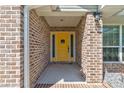 Charming yellow front door framed by brick and sidelights creates a welcoming entryway at 208 Lagoon Mist Ct, Oak Hill, FL 32759