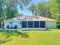 Expansive backyard featuring lush green grass, mature trees, and a screened-in patio, perfect for outdoor entertaining at 3013 Lime Tree Dr, Edgewater, FL 32141