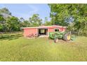 Spacious red outbuilding on a well-kept lot with a tractor at 416 Western Rd, New Smyrna Beach, FL 32168