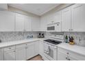 Well-equipped kitchen with sleek white cabinetry, mosaic backsplash, and modern appliances at 5300 S Atlantic Ave # 16-205, New Smyrna Beach, FL 32169