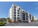 Modern condo building showcasing spacious balconies with blue railings, lush landscaping, and ample parking at 5300 S Atlantic Ave # 20-507, New Smyrna Beach, FL 32169