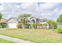 Inviting home with lush landscaping, including a palm tree, gray stucco, and attached two-car garage at 6403 Adrianne Ct, Port Orange, FL 32128