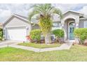 Close-up view of a gray stucco home showcasing an arched entryway, well-kept lawn, and two-car garage at 6403 Adrianne Ct, Port Orange, FL 32128