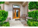 Inviting front porch showcasing a decorative bench, small side table, and lush landscaping around the entrance at 6436 Longlake Dr, Port Orange, FL 32128