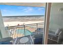 Lovely balcony view with ocean, beach, and pool with plenty of lounge chairs on a sunny day at 705 N Atlantic Ave # 4030, New Smyrna Beach, FL 32169