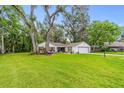 Single-story home with a lush green front lawn and mature trees at 795 Sugar Cane Ln, Port Orange, FL 32129