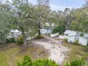 Property shot showing the garage, gravel drive and mature trees with Spanish moss providing shade at 801 Canal St, New Smyrna Beach, FL 32168