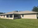 Expansive backyard with lush green grass, screened in patio, and neutral-toned exterior at 2530 Tamarind Dr, Edgewater, FL 32141