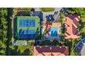 Aerial shot showcasing tennis courts, a pool, and lush landscaping within a condo community at 445 Bouchelle Dr # 301, New Smyrna Beach, FL 32169