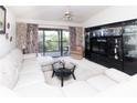 Spacious living room featuring a large balcony, entertainment center and a comfortable white sectional sofa at 445 Bouchelle Dr # 301, New Smyrna Beach, FL 32169