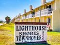 Lighthouse Shores Townhomes boasts charming yellow exterior, chimney stacks, and white balcony railings, with a community sign at 4752 S Atlantic Ave # 1, Ponce Inlet, FL 32127