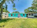 A vibrant home has a brick patio, lush lawn, outdoor bar, and brightly painted doors and trim at 650 S Pine St, New Smyrna Beach, FL 32169