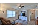 Inviting living room with custom built-in shelving, plush rug, crown moulding, and a ceiling fan at 1119 Wild Oak Ter, Deland, FL 32720