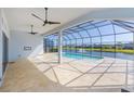 Open-air lanai with travertine tile overlooking a screened pool and lake at 6277 W Fallsgrove Ln, Port Orange, FL 32128