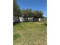 Large grassy backyard is perfect for outdoor activities, bordered by a white fence and mature trees, offering privacy at 115 Los Arbor Dr, Deland, FL 32724
