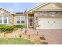 A well-maintained home exterior with brick pathway, stone details, and an American flag at 115 Los Arbor Dr, Deland, FL 32724