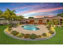 Beautiful backyard with a kidney-shaped pool, spa, and lush landscaping at dusk at 2548 E Compton St, Orlando, FL 32806