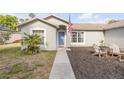 Close-up of a home's front yard with tidy landscaping, a vibrant palm tree, and Adirondack chairs on mulch at 2713 Needle Palm Dr, Edgewater, FL 32141