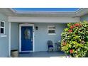 Front porch with a bright blue door, adorned with a decorative chair and lush foliage at 34 Richmond Dr, New Smyrna Beach, FL 32169
